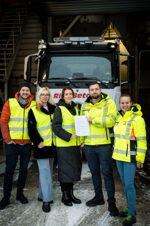 fem mennesker i refleksvest står foran en betongbil